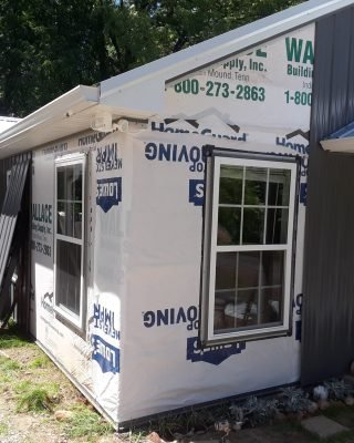 Home addition under construction with exterior framing and building wrap installation